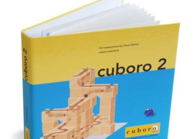 Publikacja z konstrukcjami przestrzennymi do odwzorowania Cuboro 2 – otwarta broszura z przykładową konstrukcją na okładce