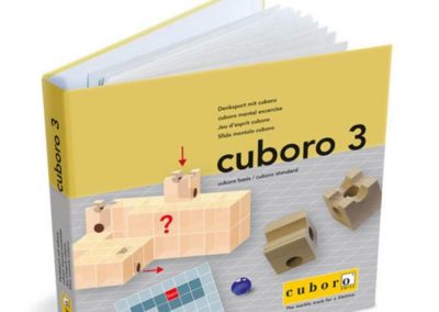 Publikacja z łamigłówkami przestrzennymi Cuboro 3 – otwarta broszura z przykładową łamigłówką na okładce