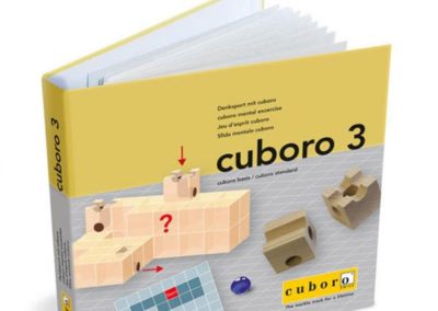 Publikacja z łamigłówkami przestrzennymi Cuboro 3 – otwarta broszura z przykładową łamigłówką na okładce